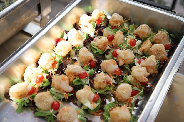 Ensalada de camarones fritos con crema que se arregla en tamaño de bocado en línea buffet. El contenedor es una bandeja rectangular de acero inoxidable. Enfoque selectivo.