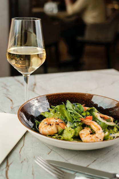 Ensalada con camarones y hierbas con vino blanco Plato de mariscos en café