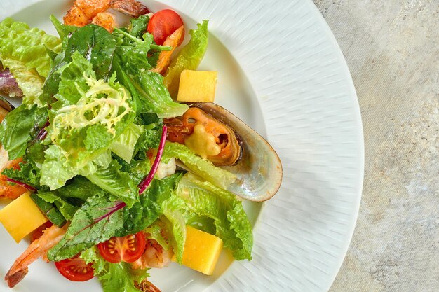 Ensalada de camarones y mejillones, mango en un plato blanco sobre un mantel