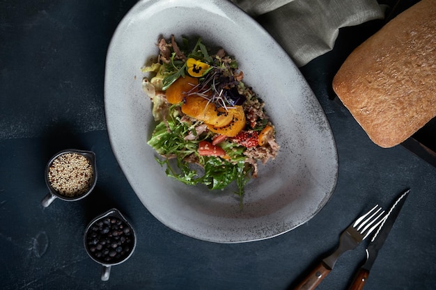 Ensalada con cangrejo y aguacate sobre un fondo oscuro Hojas de ensalada de rúcula sazonadas con salsa de vino blanco con carne de cangrejo y aguacate a la parrilla en un enfoque suave Vista superior