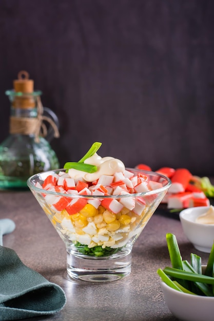 Ensalada de cangrejo de palitos de pescado, huevos, cebollas y maíz en un bol sobre la mesa Vista vertical