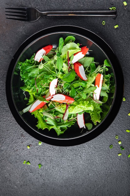 Ensalada de cangrejo palo hojas de lechuga verde mezclar pétalos porción fresca comida bocadillo en la mesa espacio de copia