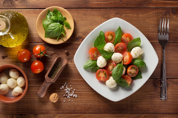 Ensalada caprese e ingredientes en madera