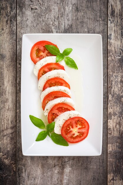 Ensalada Caprese e ingredientes sobre madera