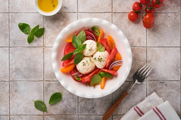 Ensalada caprese Ensalada caprese italiana con rodajas de tomate queso mozzarella albahaca aceite de oliva en un plato blanco sobre fondo blanco Deliciosa comida italiana Vista superior Estilo rústico