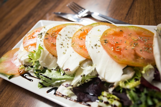 La ensalada Caprese es una ensalada italiana hecha de tomates en rodajas y mozzarella fresca y albahaca fresca.