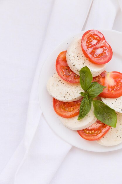 Ensalada Caprese italiana fresca con tomates con queso mozzarella y albahaca en un plato blanco Comida saludable