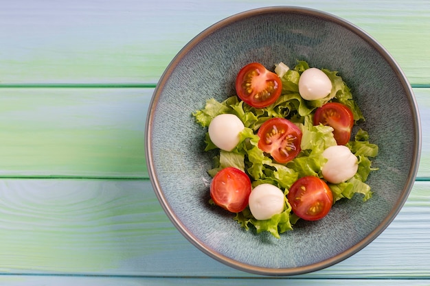 Ensalada caprese italiana con queso mozzarella, tomate y albahaca, en un plato. Vista superior