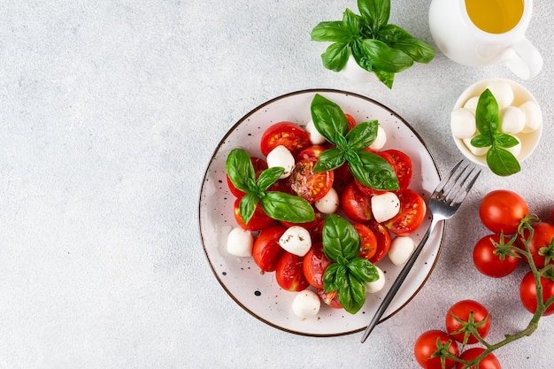 Ensalada caprese italiana con rodajas de tomate mozzarella albahaca aceite de oliva sobre un fondo claro Vista superior Comida italiana Ensalada saludable Comida de verano