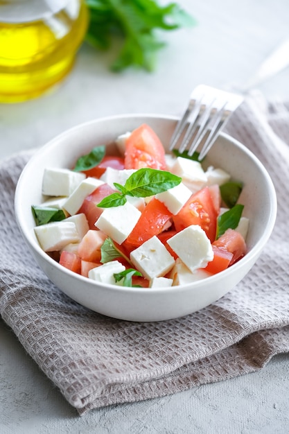 Ensalada caprese italiana con rodajas de tomate mozzarella albahaca aceite de oliva sobre un fondo claro