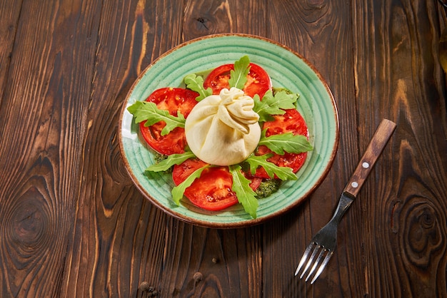 Ensalada caprese italiana con tomate y queso sobre mesa de madera