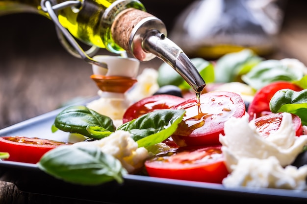 Ensalada Caprese Mozzarella, tomates cherry, albahaca y aceite de oliva en la mesa de roble antiguo cocina italiana