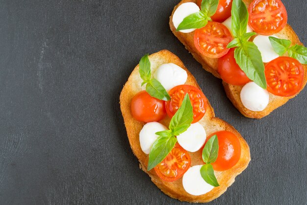 Ensalada Caprese con tomates maduros y mozzarella con hojas frescas de albahaca. Comida italiana.