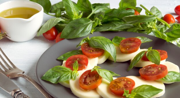 Ensalada Caprese Con Tomates Maduros Y Mozzarella Con Hojas Frescas De Albahaca. Comida italiana.