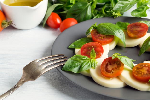 Ensalada Caprese Con Tomates Maduros Y Mozzarella Con Hojas Frescas De Albahaca. Comida italiana.