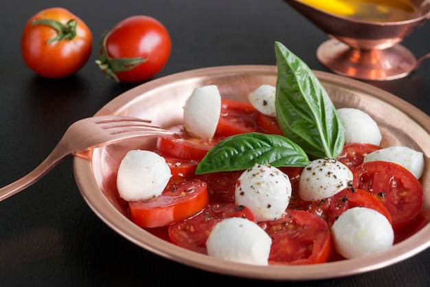Foto ensalada caprese con tomates maduros y mozzarella con hojas frescas de albahaca. comida italiana.