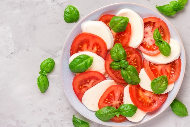 Ensalada caprese con tomates maduros y queso mozzarella, hojas de albahaca fresca. comida italiana