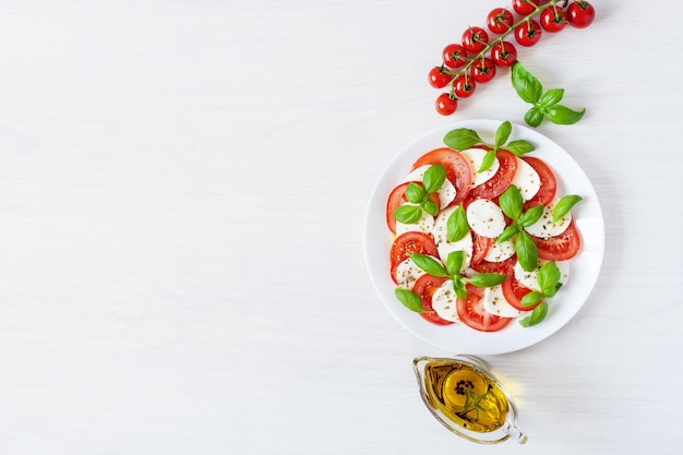 Ensalada Caprese con tomates mozzarela aceite de oliva fresco y albahaca sobre fondo blanco vista superior