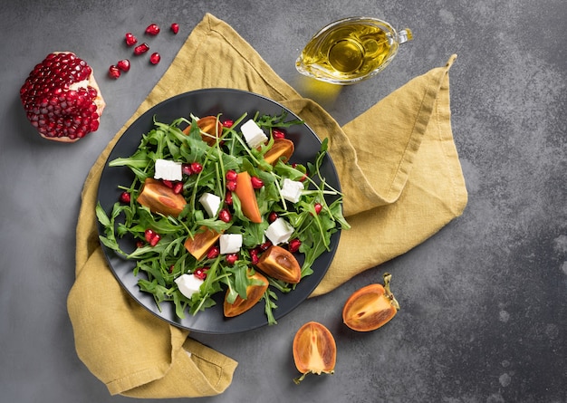 Ensalada de caqui con rúcula, queso feta y granada Concepto de comida sana