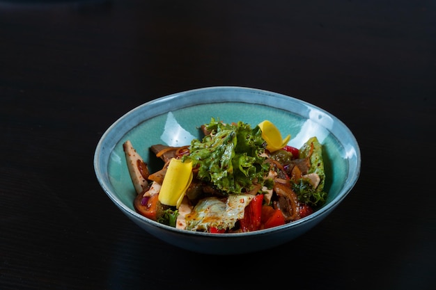 Ensalada con carne y verduras sobre un fondo negro