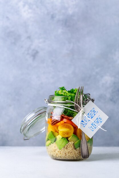 Ensalada casera en frasco de vidrio con quinua y verduras con etiqueta a la hora del almuerzo sin plástico y concepto para llevar