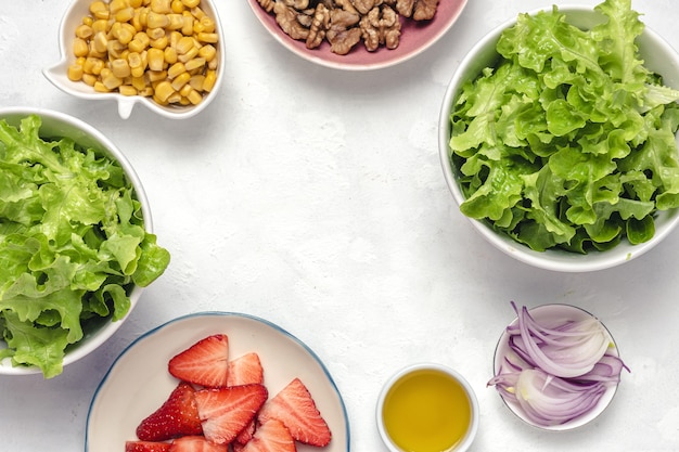 Ensalada casera con lechuga, fresas, cebolla morada, maíz; aceite de oliva y nueces en un bol. Concepto de comida vegana