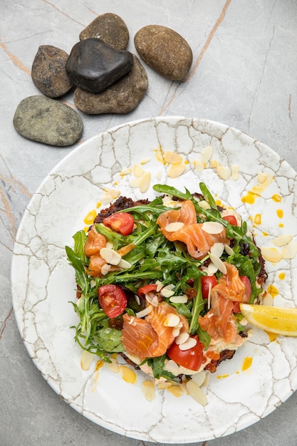 Ensalada con cerezas de hierbas de caviar de salmón sobre una mesa de piedra blanca en un restaurante