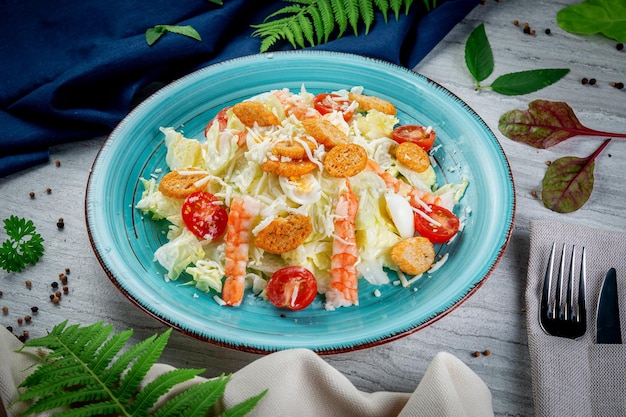 Ensalada César con camarones en un plato sobre una mesa de luz