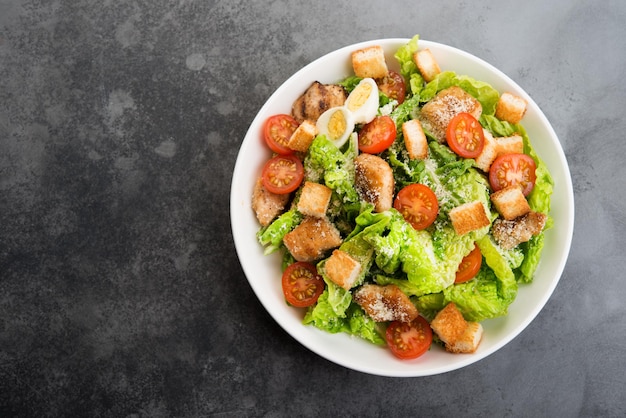 Ensalada César con filete de pollo, tomates cherry y picatostes, comida tradicional italiana, vista superior, espacio de copia