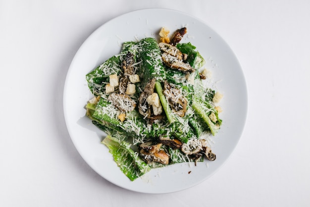 Ensalada César de ostras servida en plato blanco sobre mantel blanco