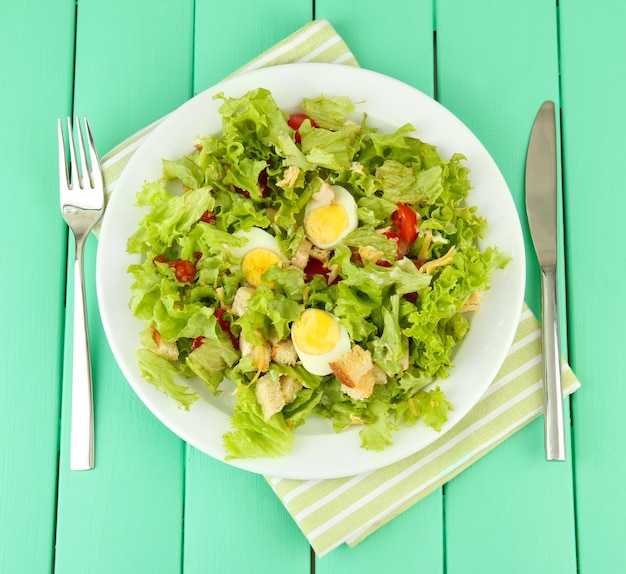 Ensalada César en plato blanco sobre fondo de madera de color