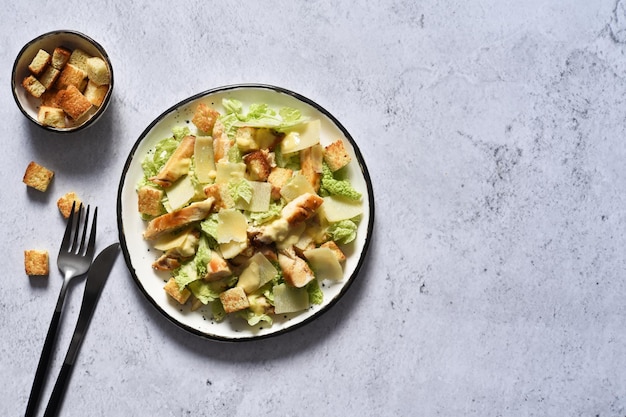 Ensalada César en un plato sobre un fondo de hormigón, vista superior.