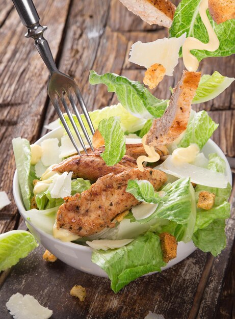 Ensalada César con pollo y verduras en una mesa de madera