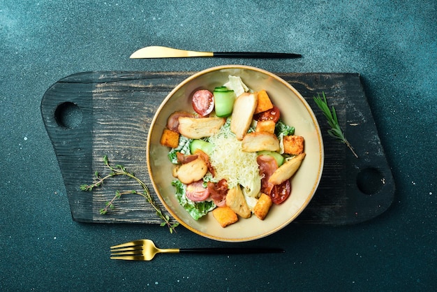 Ensalada César con pollo y verduras en un plato Restaurante que sirve de cerca sobre un fondo de piedra oscura