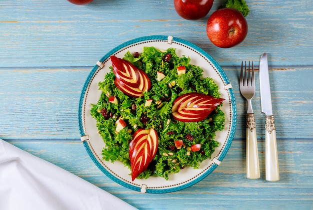 Ensalada de col rizada verde con manzana roja, arándano y semillas de girasol.