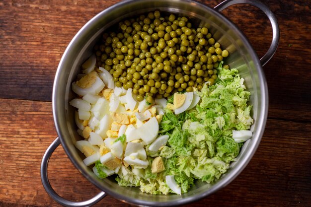 Ensalada de col de Saboya Los ingredientes están en una cacerola guisantes huevos de gallina y col Preparando una ensalada vegetariana