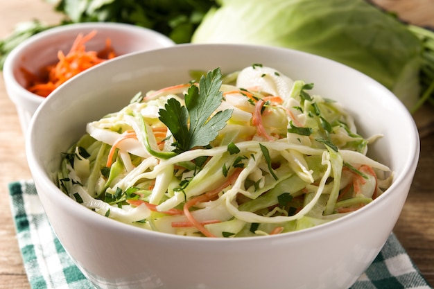 Ensalada de col en un tazón blanco sobre mesa de madera