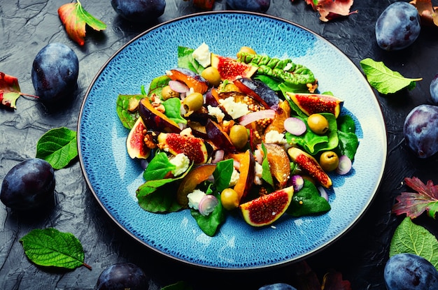 Ensalada colorida con ciruelas, higos, aceitunas y queso feta. Ensalada otoñal de frutas y verduras.