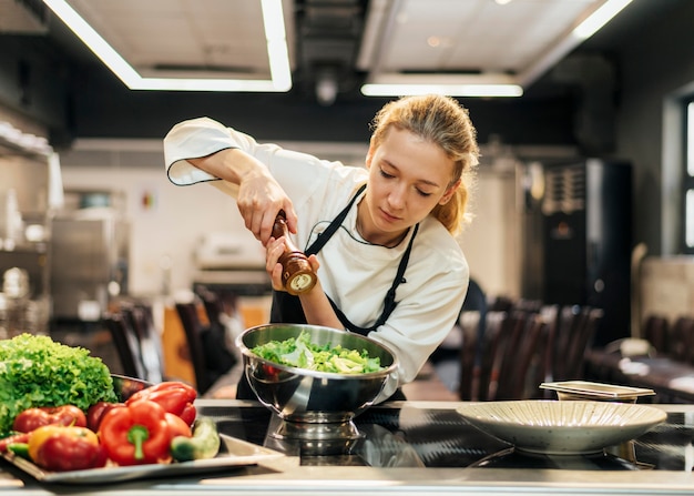 Foto ensalada de condimentos chef femenina en la cocina