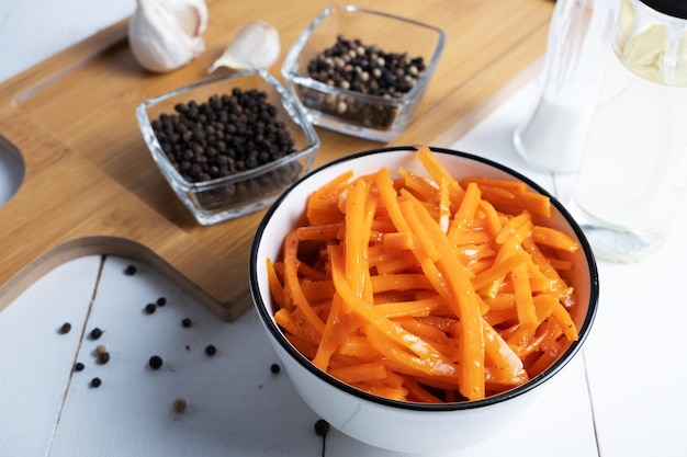 Ensalada coreana picante y picante de zanahorias y salsa con pimienta molida en una ensaladera ligera