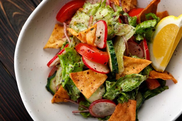 Una ensalada deliciosa y nutritiva con verduras frescas y patatas fritas crujientes sobre un fondo de madera