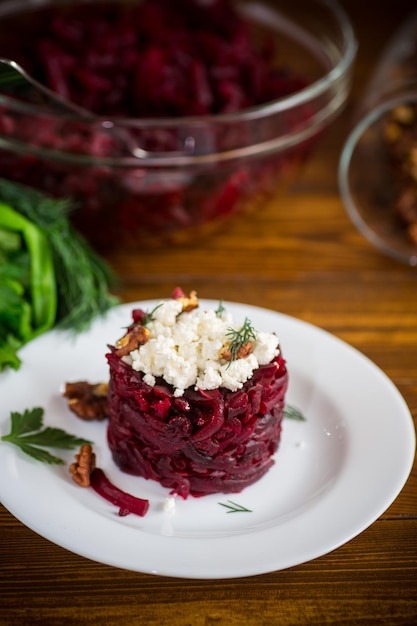 Ensalada dietética de remolacha hervida con nueces y requesón sobre una mesa de madera