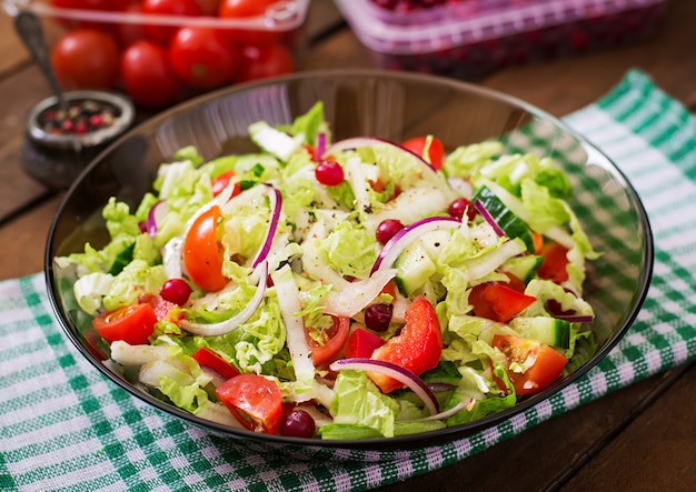 Ensalada dietética con verduras frescas (tomate, pepino, col china, cebolla roja y arándanos)