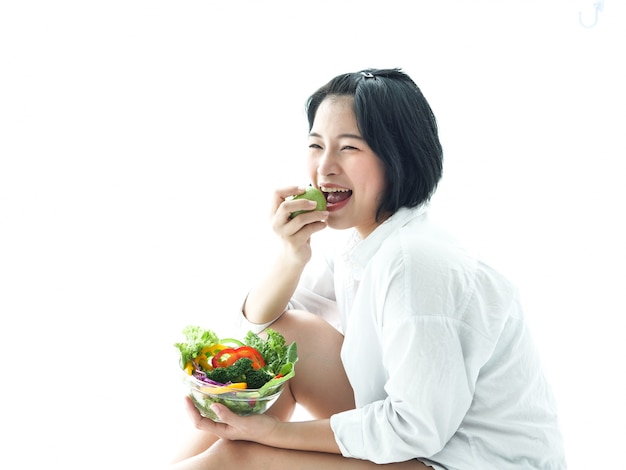 Ensalada eatiing asiática de la mujer joven en la comida blanca de la dieta del fondo