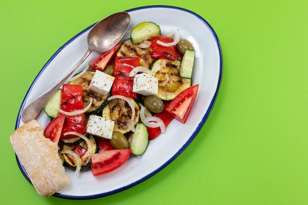 Ensalada con ensalada fresca y a la parrilla en un plato blanco sobre verde