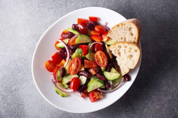 Ensalada española con frijoles rojos y verduras en una placa blanca.