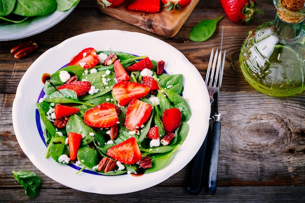 Ensalada de espinacas con fresas, queso de cabra balsámico y nueces sobre fondo de madera