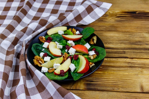 Ensalada de espinacas de otoño con nuez de queso feta de manzana y arándano seco sobre mesa de madera Comida vegetariana saludable