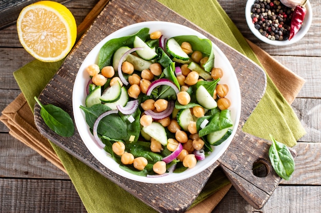 Ensalada de espinacas, pepino, garbanzos, cebollas y limón en una mesa de madera