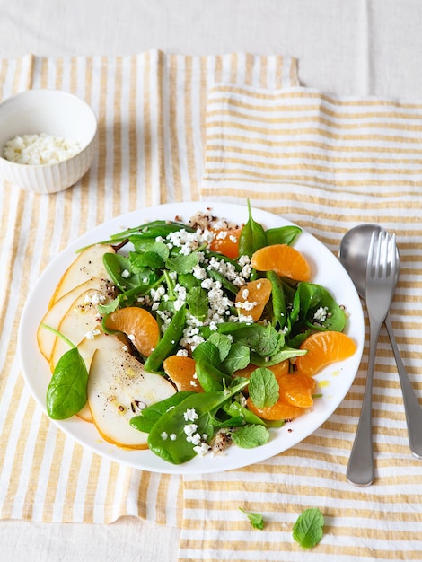 Ensalada de espinacas y quinoa con peras, naranjas y ricotta. Preparación de comidas saludables. Platos a base de plantas. Vida verde. Receta vegana. Peinado de alimentos. Cocina vegetariana. Alimentación saludable. Concepto de comida para bajar de peso.